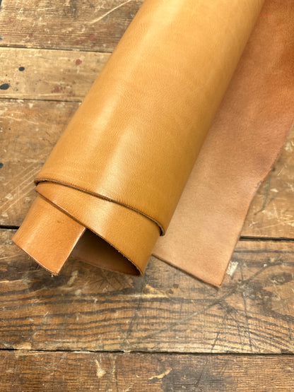 ROLLED NATURAL BULL DOUBLE SHOULDER HIDE ON DISTRESSED WOOD BACKGROUND